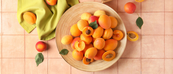 Plate of sweet apricots on pink background, top view