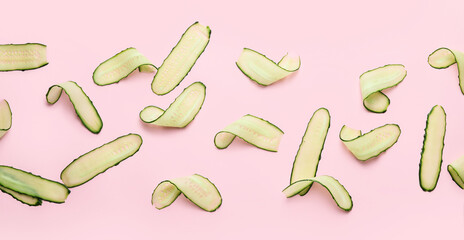 Many sliced cucumbers on pink background, top view