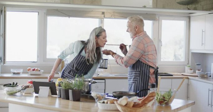 Middle aged caucasian couple preparing meal, cooking together in kitchen at home, slow motion