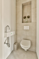 a bathroom with a white toilet and a mirror on the wall above it is a flower in a glass vase