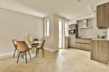 a kitchen and dining area in a house with hardwood flooring, white walls and light wood cabinets on either side
