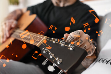 Young tattooed man playing guitar at home, closeup