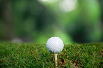 Golf ball set on tee with green bokeh background