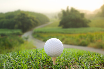 A golf ball is placed on the grass with a mountain view behind.