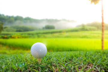 A golf ball is placed on the grass with a mountain view behind.
