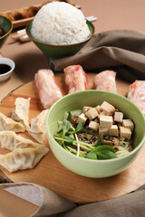 Wooden board with tasty Chinese dishes on color background, closeup