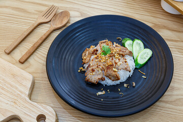 Stir-Fried Pork with Garlic and pepper with cooked thai jasmine rice in black plate, popular Thai Street food.