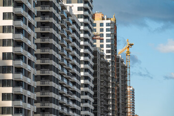 Row of new multi apartment houses and construction crane
