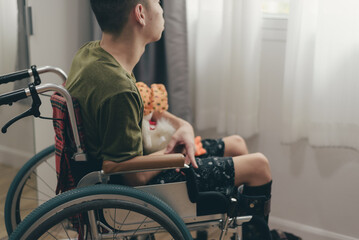 Young man with disability on wheelchair hug doll in the bedroom lonely, Depression occurs in people with disabilities who are alone at home, World mental health day and mental rehabilitation concept. - obrazy, fototapety, plakaty