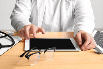 Female doctor working with tablet computer on wooden medical desk, closeup