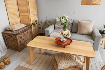 Interior of living room with sofa and ikebana on table