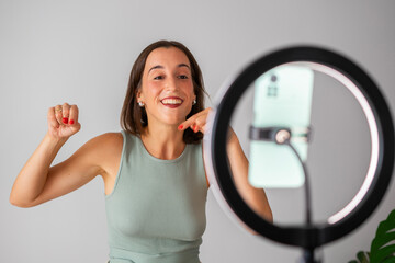 Influencer girl. happy girl recording a video for social networks. She is pointing down with her...