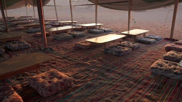 Lunch tables for tourists inside bedouin tent at sunset in a camp in the desert
