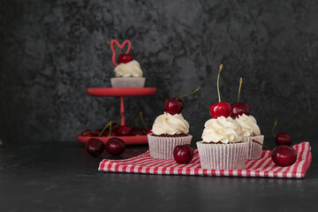 Tasty cherry cupcakes on black background