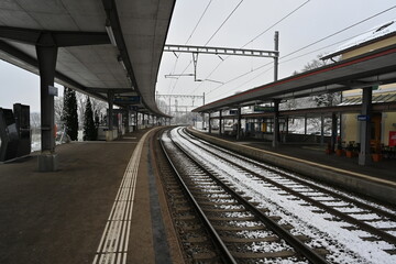 Fototapeta na wymiar Railway platform of a small village station in winter. There is snow on the railway tracks. 