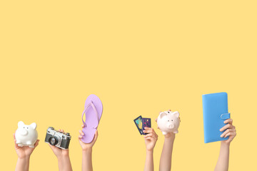 Female hands with piggy banks, photo camera, flip flop and credit cards on beige background. Travel...