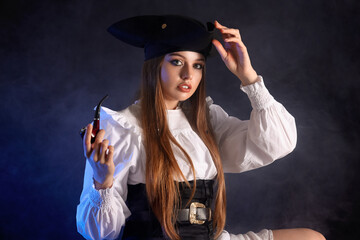 Beautiful female pirate with smoking pipe on black background