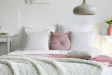 Cozy bed with white blanket and pillows in bedroom
