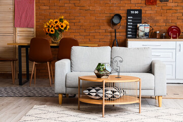 Interior of modern open space kitchen with grey sofa, coffee table and white counters