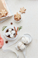 Cozy Christmas background with cup of cocoa, marshmallows, ginger snowflakes cookies, cinnamon sticks and books at cozy home flat lay. Copy space