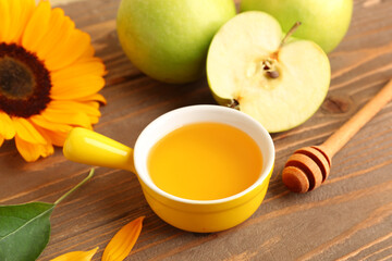 Bowl of honey with apples and sunflower for Rosh Hashanah celebration (Jewish New Year) on wooden table