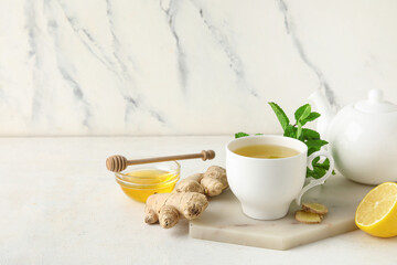 Cup of ginger tea and bowl with honey on white background