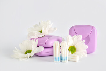 Menstrual tampons, storage boxes and chamomile flowers on white background