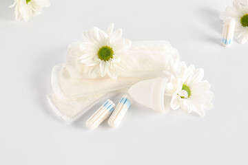 Fototapeta na wymiar Female hygiene items and chamomile flowers on light background