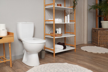 Fototapeta na wymiar Interior of modern restroom with toilet bowl and shelving unit