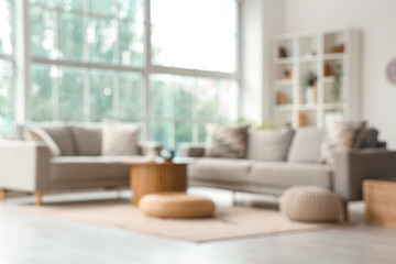 Blurred view of living room with sofas, table and poufs