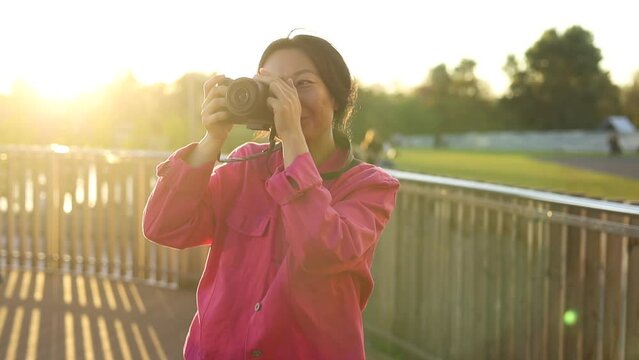 Asian woman use of digital camera to take photo in city in the evening. asian traveler taking a photo at sunset. Solo travel concept.