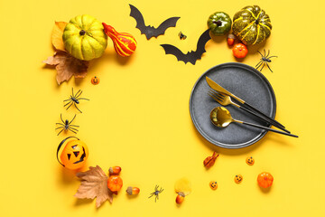 Obraz na płótnie Canvas Frame made of table setting with pumpkins and Halloween decor on yellow background