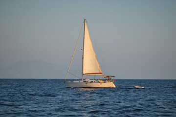 Obraz premium Sailing yacht on the open sea at sunset.