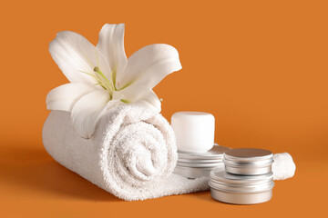 Obraz na płótnie Canvas Set of cosmetic products, clean towel and lily flower on color background