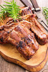 Barbecue veal spare ribs sliced with hot honey chili marinade served as close-up on a rustic design cutting board