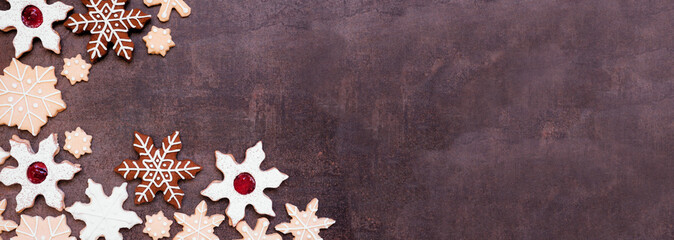 Christmas baking corner border with an assortment of snowflake cookies. Overhead view on a dark stone banner background with copy space. Holiday baking concept.