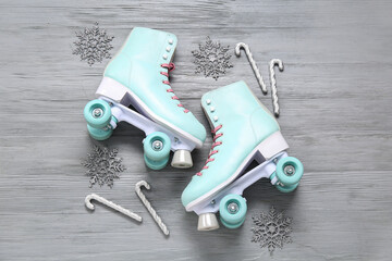 Composition with vintage roller skates and Christmas decorations on grey wooden background