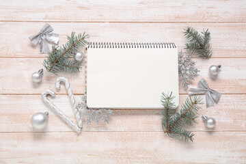 Composition with blank notebook, fir branches and Christmas decorations on light wooden background