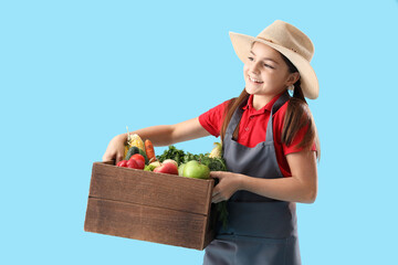 Fototapeta premium Little farmer with fresh food on blue background