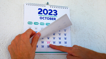 A beautiful November page of the wall calendar 2023 and a man points a finger at the marked...