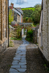 View down a flagstone alleyway of a quaint private stone gate with flowers and vines