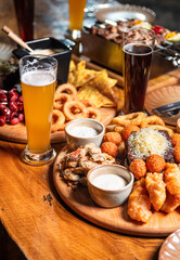 Beer appetizer assorted salted peanuts, sausages and croutons with garlic in a plate on a wooden table. Vertical orientation, close-up, no people