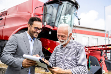 Farmer signing contract and buying new combine harvester machine.