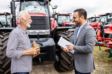 Farmer and dealer negotiating about the price of new tractor agricultural machines.