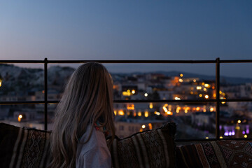 Blonde woman looking Cappadocia town with lights of the street in the night