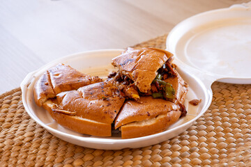 Italian pieces of shawarma full of peppers and BBQ sauces with chicken on white plate with straw on table