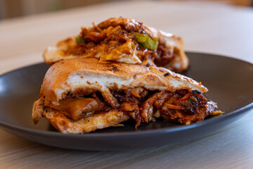 Italian pieces of shawarma full of peppers and BBQ sauces with chicken on black plate on wooden table table with dips