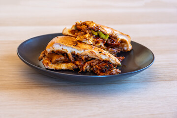 Italian pieces of shawarma full of peppers and BBQ sauces with chicken on black plate on wooden table table with dips