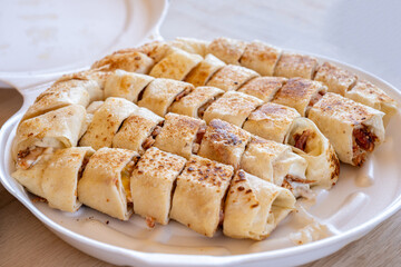 Pieces of shawarma on wooden table with dips and arranged on white plate