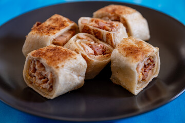 Shawarma pieces on black plate with blue background isolation  and copy space